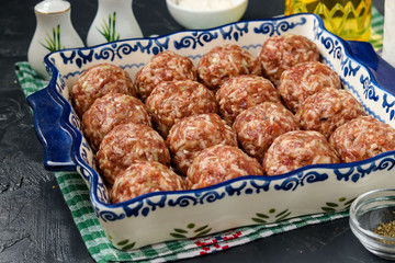 Meatballs raw with rice are cooking in ceramic form, horizontal orientation