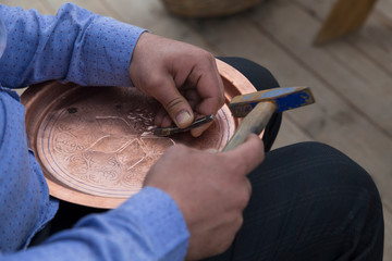 the man making pattern on the copper plate