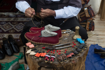 the man making colorful traditional leather shoes carefully.