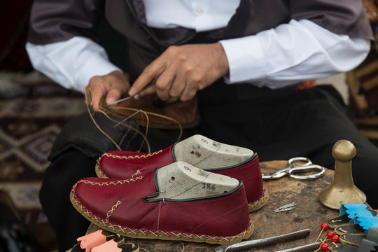 the man making colorful traditional leather shoes carefully.