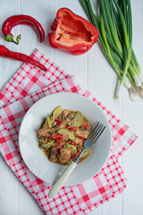 Hot salad with chicken, zucchini and chili pepper, sprinkled with sesame seeds and herbs. Asian food. Dark wooden background.