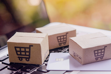 Online shopping - Paper cartons or parcel with a shopping cart logo and credit card on a laptop...