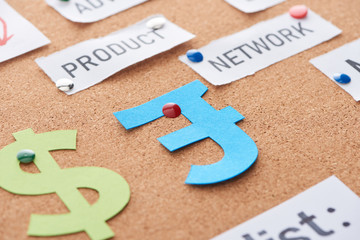 color paper cards with product and network inscriptions and currency signs pinned on cork office board