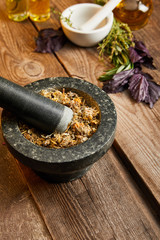 Obraz na płótnie Canvas mortars with pestles with herbal mix near fresh basil on wooden surface