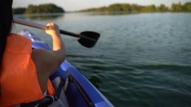 A girl floats in a kayak boat on the river and rowing an oar. Slow motion