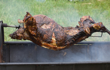 carcass of a young sheep roasting on a spit over low heat