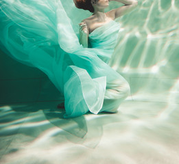 young woman swimming alone with fashion fabric underwater incognito