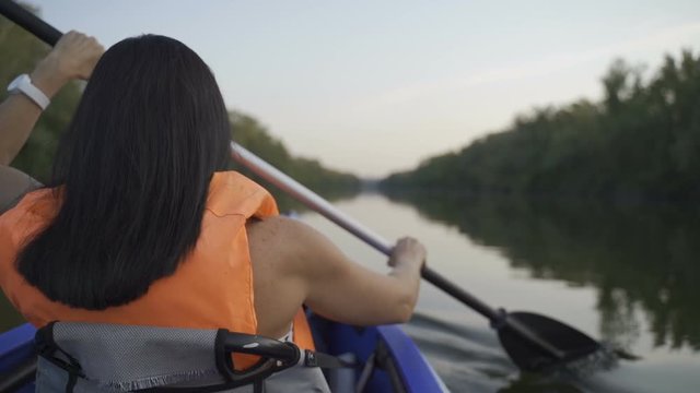 A girl floats in a kayak boat on the river and rowing an oar. Slow motion