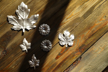 A composition with a hard shadow, in which there are silver flowers and a maple leaf; on a brightly...
