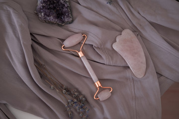 Rose quartz guasha stone and roller. Beauty anti-ageing concept. Top view - obrazy, fototapety, plakaty
