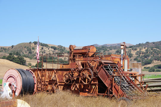 View of an abandoned defunct rusty and rotten agricultural farm equipment on a rural field