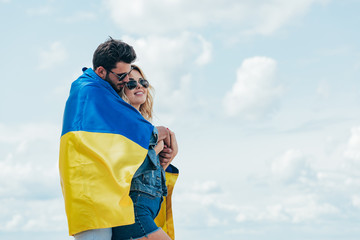 Naklejka premium attractive woman and handsome man smiling and holding ukrainian flag