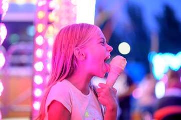 Beautiful girl eating a rich cream ice cream at fair