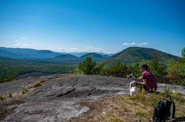 Woman and dog enjoying the view of Adirondack mountain range from the summit of Clark Mountain