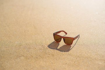Fototapeta na wymiar Brown sunglasses on the beach and holiday