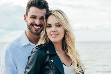 attractive woman and handsome man smiling and hugging outside