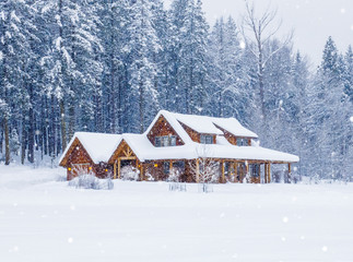 Rural country vacation house home in snowy winter with lights on and snowing
