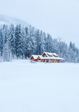 House home rural country cabin in the mountains with lights on at dusk twilight in  snowy winter landscape setting location