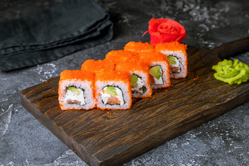 California roll with salmon on the board on grey concrete table