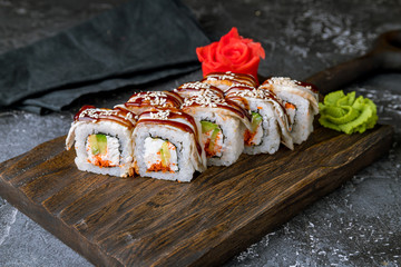 The dragon roll with eel on the board on grey concrete table