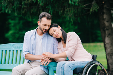 happy disabled woman with smiling handsome boyfriend resting in park together