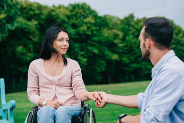 Obraz premium happy disabled woman holding hands with boyfriend while resting in park together