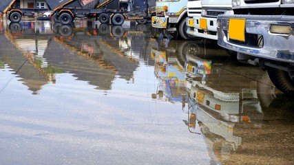 Low section of trucks parked in flood parking lots during waiting to transfer goods after heavy raining, focus at truck in foreground 
