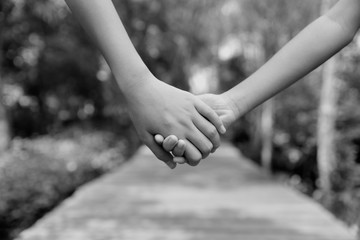 Two children holding hands each other on the wooden way and natural background in the morning. Friendship Day, Best Friend concept.