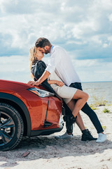 attractive woman and handsome man kissing on car outside
