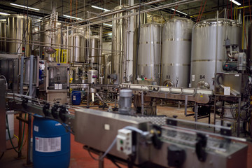 Beer assembly line conveyor belt and brewing tanks in a brewery plant