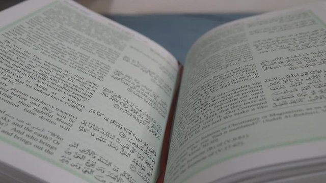 A panning shot of open pages of Quran in Arabic and English.