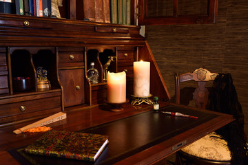 Antique secretary writing desk in dark room with candles