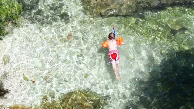 Boy snorkeling in sea with diving pipe and inflatable flippers