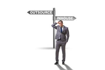 Businessman at crossroads deciding between outsourcing and inhou