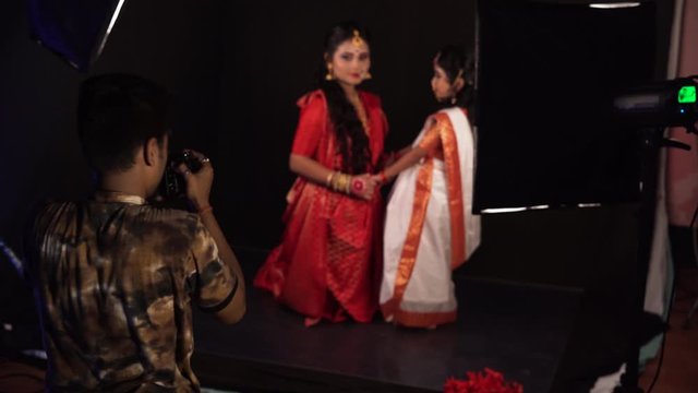 Selective focus of Indian photographer taking photos of mother and daughter in traditional saree clothes