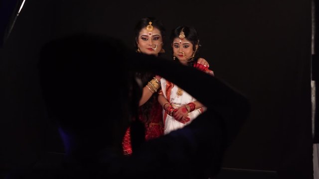 Selective focus of mother and daughter in traditional saree clothes in photoshoot, View from behind photographer