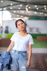 Nerdy Asian woman in white t-shirt and ripped jeans