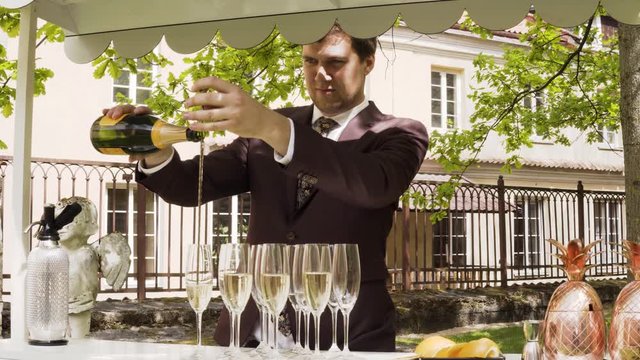 Bartender fills champagne into glasses throught the spoon. Trendy bar service in a private party. Slide right.