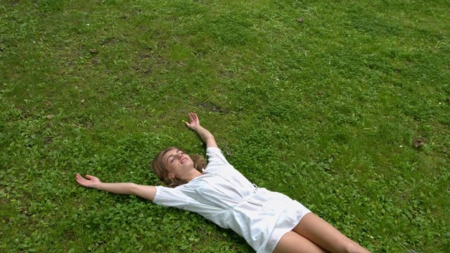 Attractive young woman is laying in the grass and enjoy the feeling.
