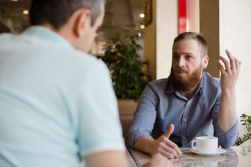 two men discussing difficult issues with emotions during coffee break in cafe talking about problems of business negotiation