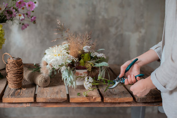 Female professional florist prepares the arrangement of wild flowers.