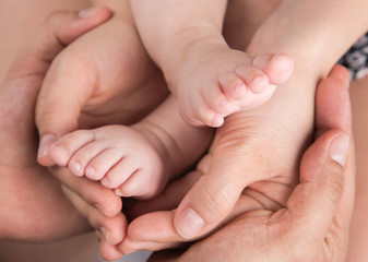 Hands of mother and father  hold baby feet