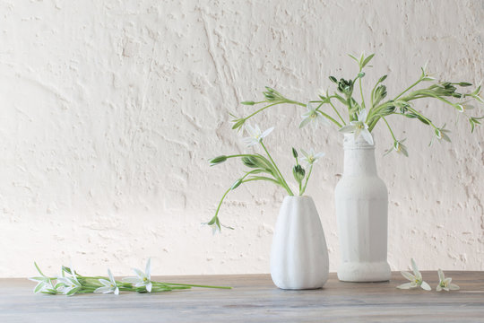 white flowers in vase on background old white wall
