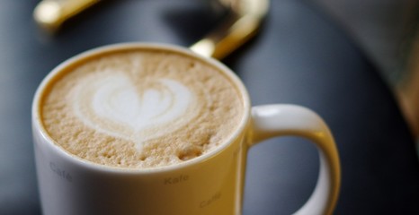 Heart shape cappuccino coffee art foam in white mug closeup view