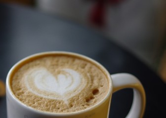heart shaped cappuccino latte art foam in white mug on black table with copy space