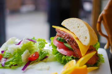 Submarine sandwich with corned beef sliced cheese cucumber lettuce tomato and peeled orange on...