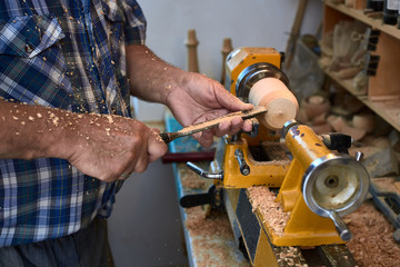 The woodturner work. Man's arms with cutter in action.
