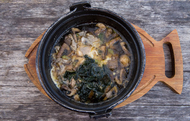 Hot thick mushroom soup with beef, spices, meat broth. Delicious soup in metal pan on wooden rustic table