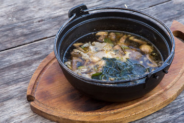 Hot thick mushroom soup with beef, spices, meat broth. Delicious soup in metal pan on wooden rustic table