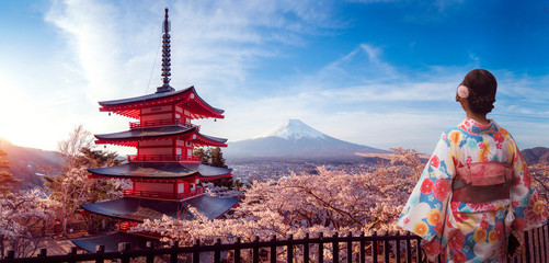 Japanisches Mädchen im Traitionalkleid des Kimonos geht im Sakura-Park mit Fuji-Berghintergrund